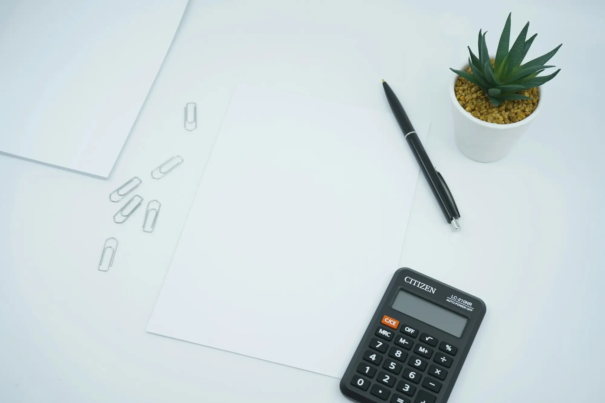 Paperwork, calculator and pen laid out on a desk for end of financial year