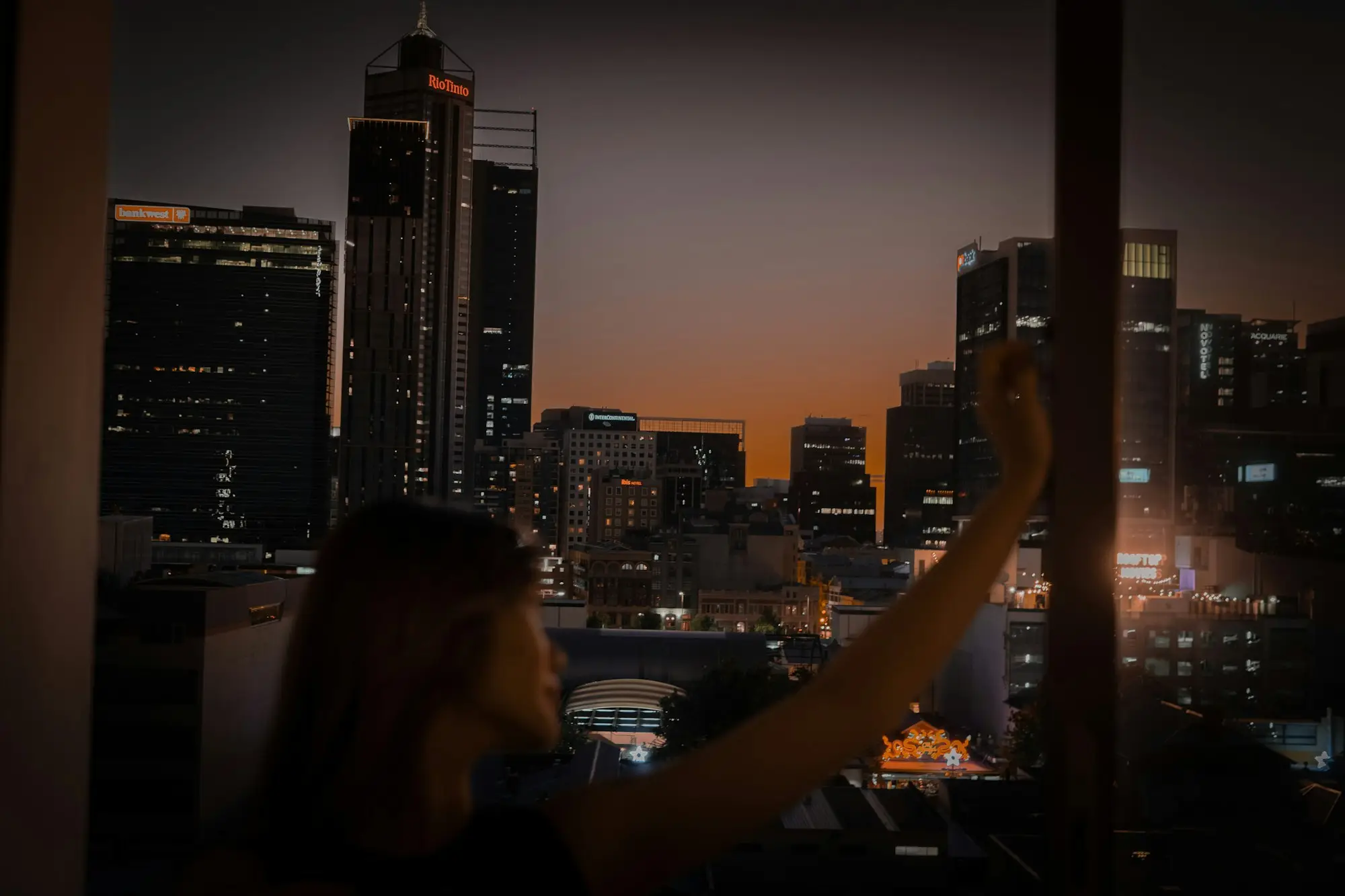 Business owner on a laptop at dusk with the Perth city skyline behind