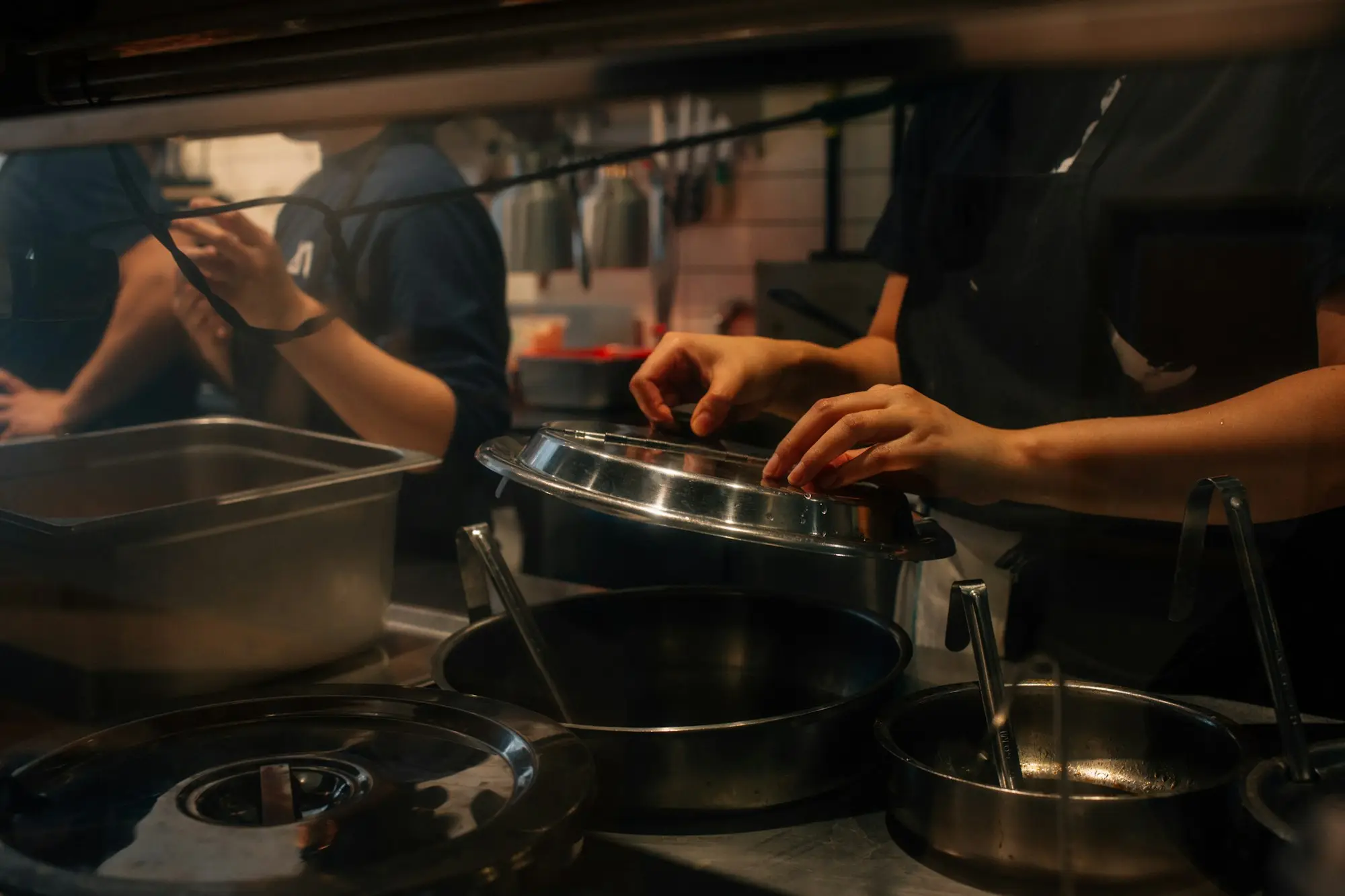 Kitchen team preparing pans and equipment before service