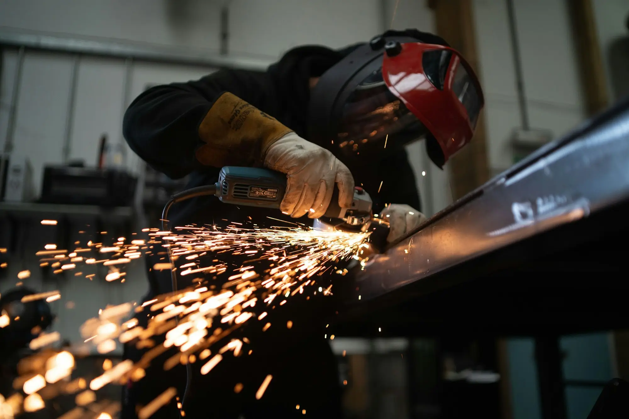 Fabrication worker cutting steel with sparks flying in a workshop